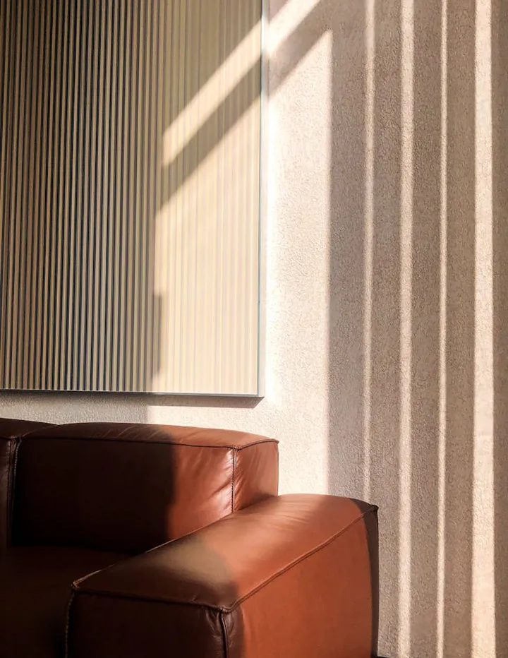 Fluted wall in afternoon light beside a tan leather armchair